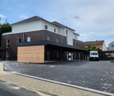 Moderne Wohngebäude mit Holzverkleidung und überdachtem Parkplatz.