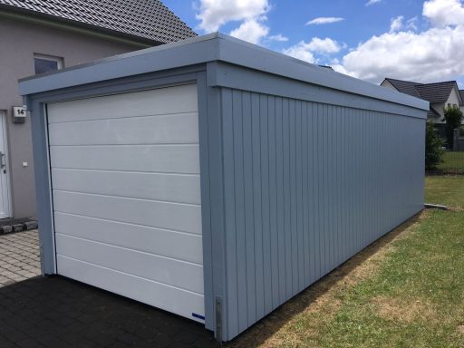 Grau gestrichene Garage mit einem weißen Rolltor und blauen Wänden.